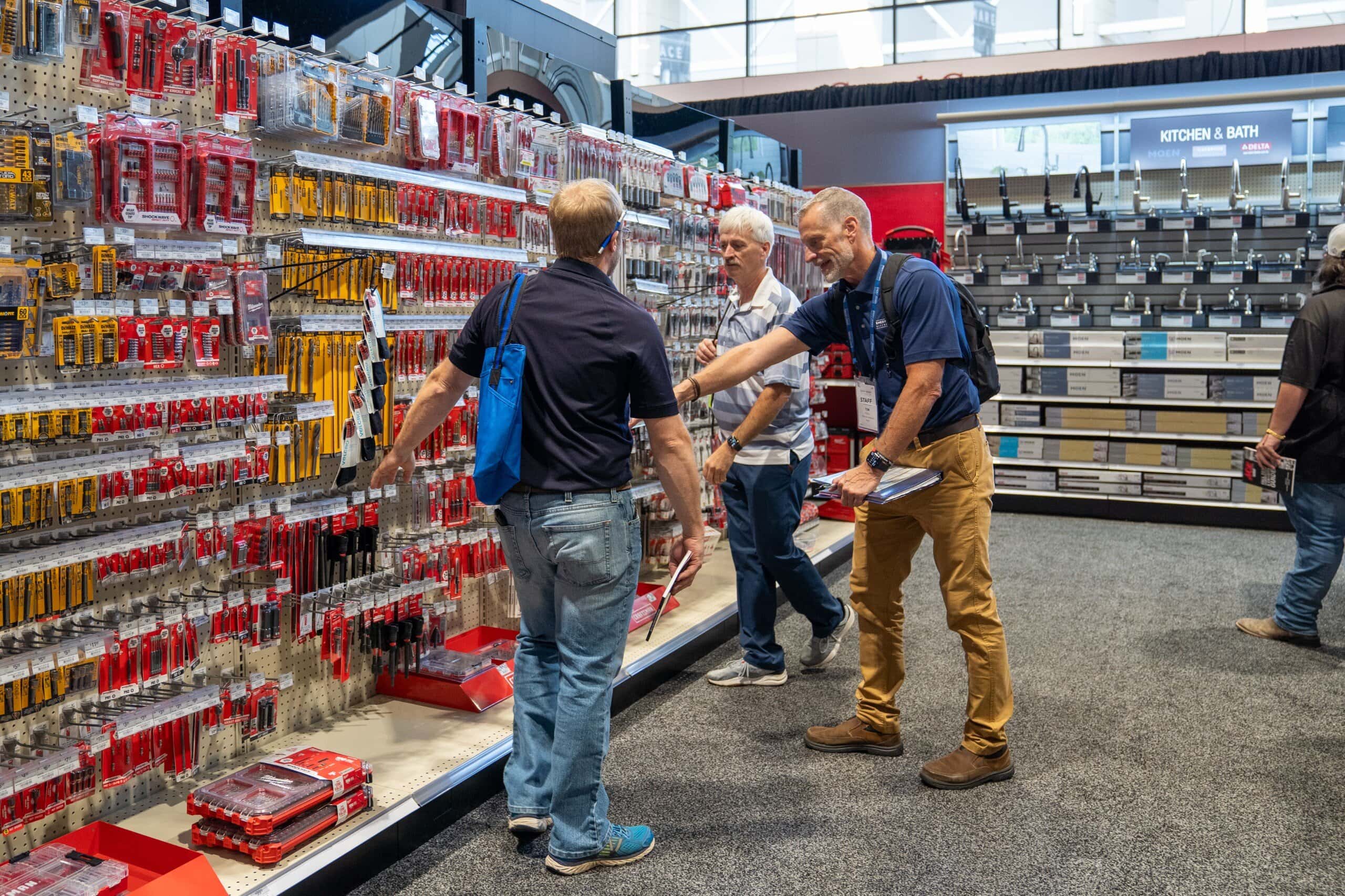 Men browsing tools in hardware store aisle.