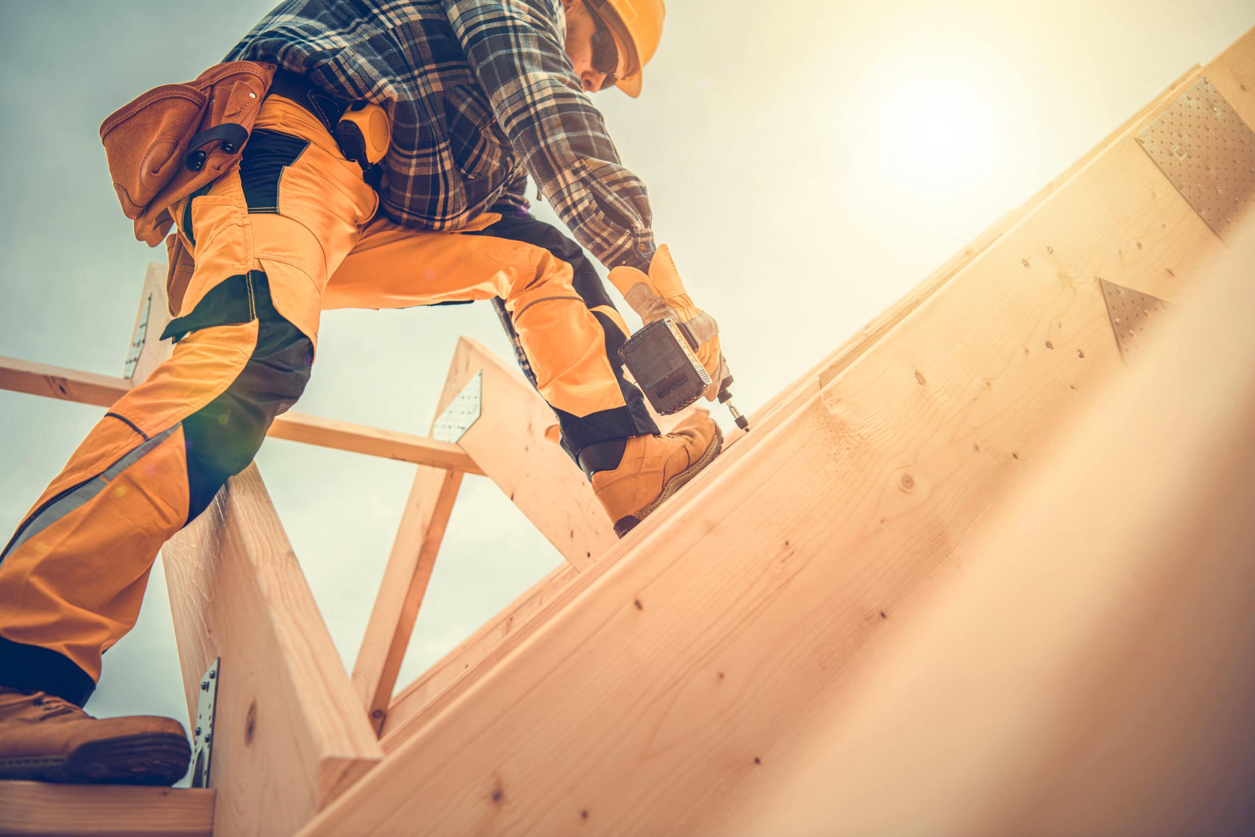 Construction worker building wooden structure with drill
